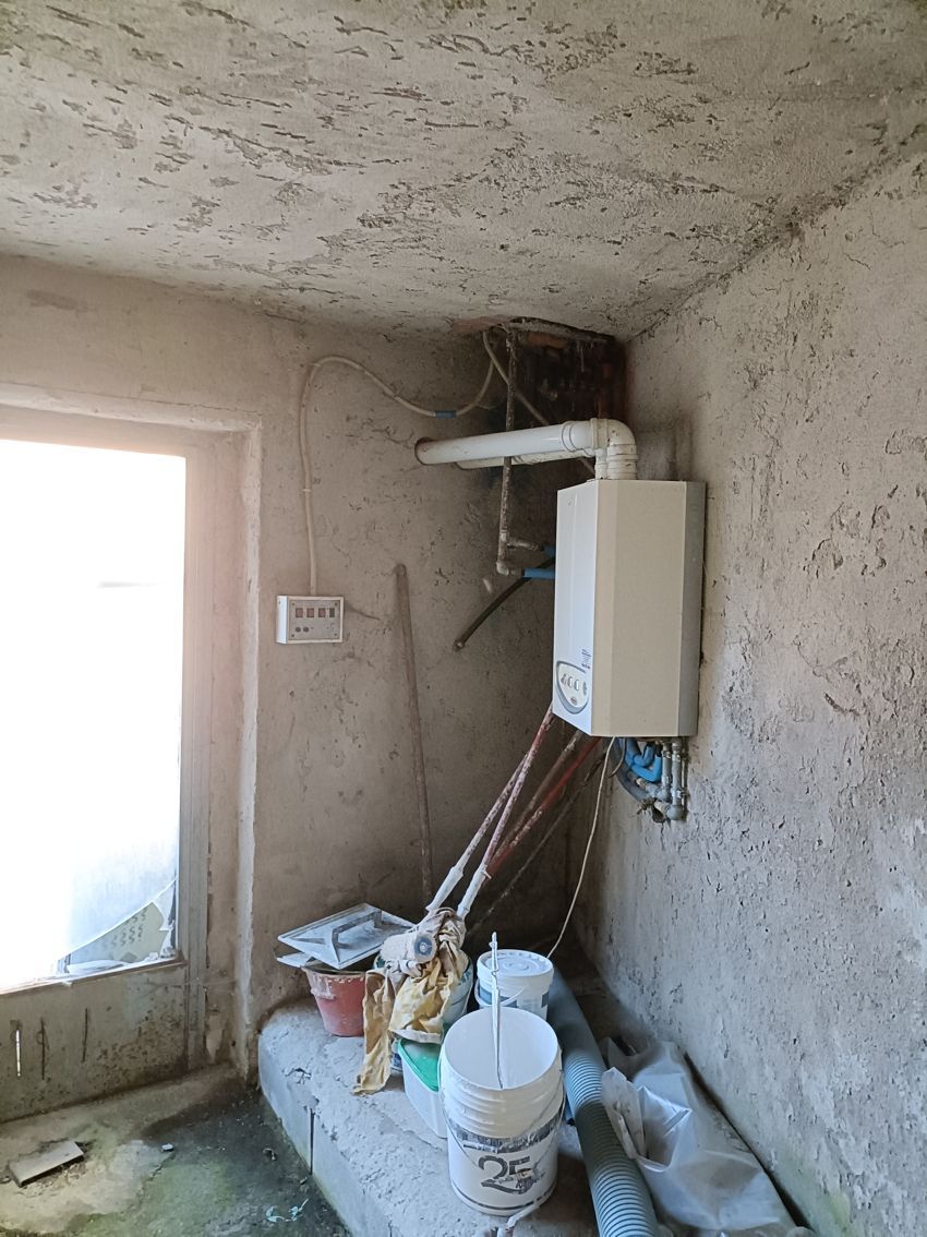 Una stanza con una stufa sul muro e dei secchi sul pavimento.