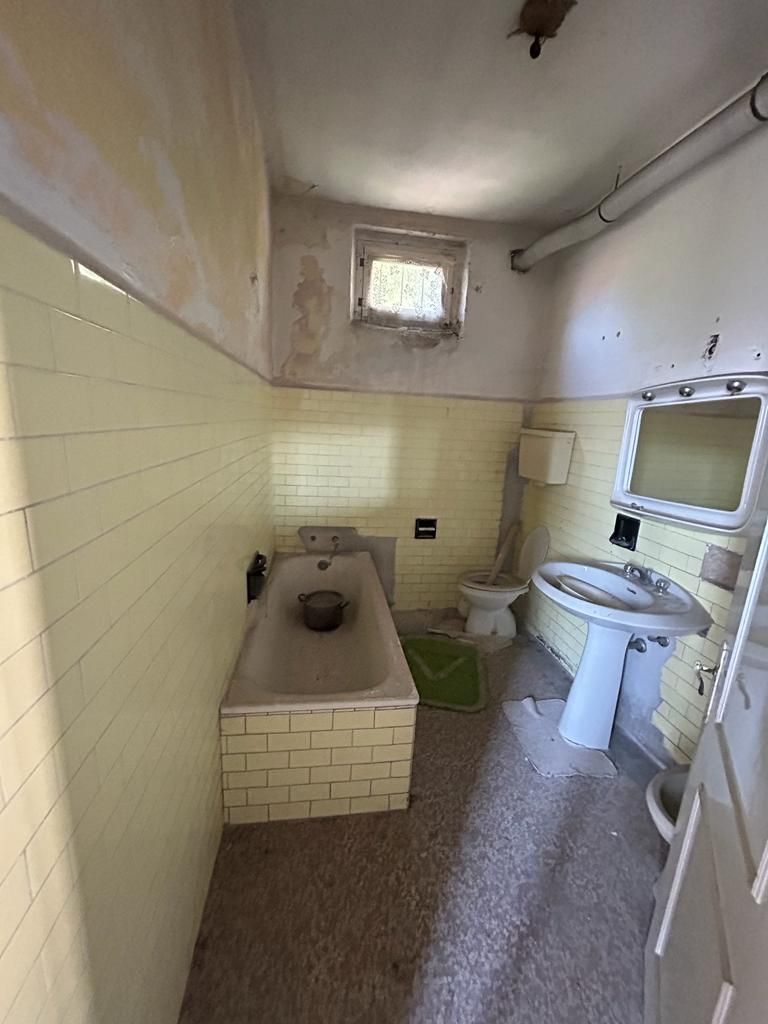 Un bagno con vasca, lavandino, water e specchio.