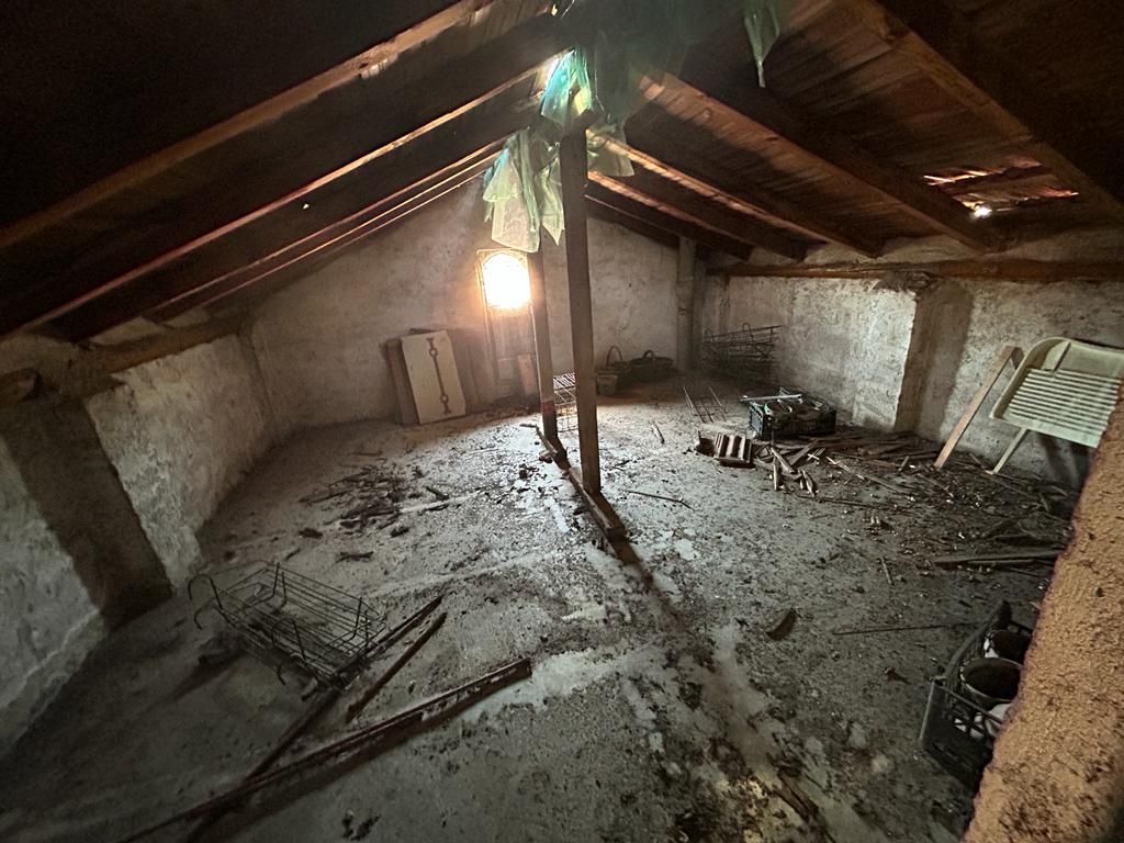 Una soffitta con il tetto in legno e un sacco di spazzatura sul pavimento.