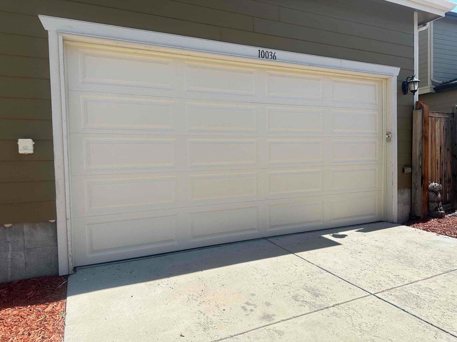 A white garage door is sitting on the side of a house.