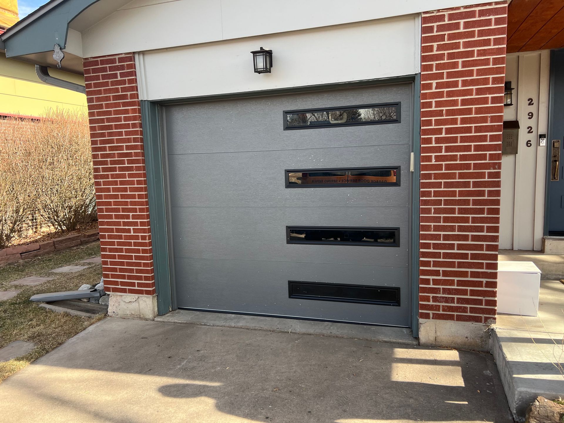 New single garage door installed. Flush panel in color charcoal with contemporary slimline windows.