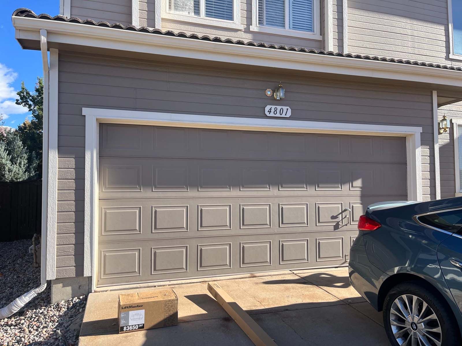 A car is parked in front of a garage door.