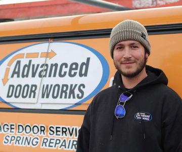 A man standing in front of an orange sign that says advanced door works