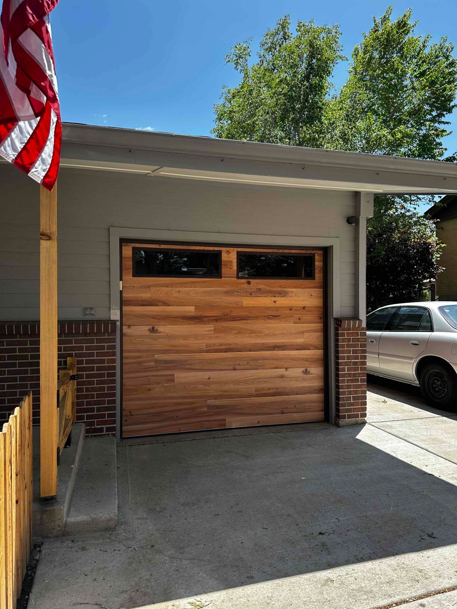A car is parked in front of a wooden garage door.