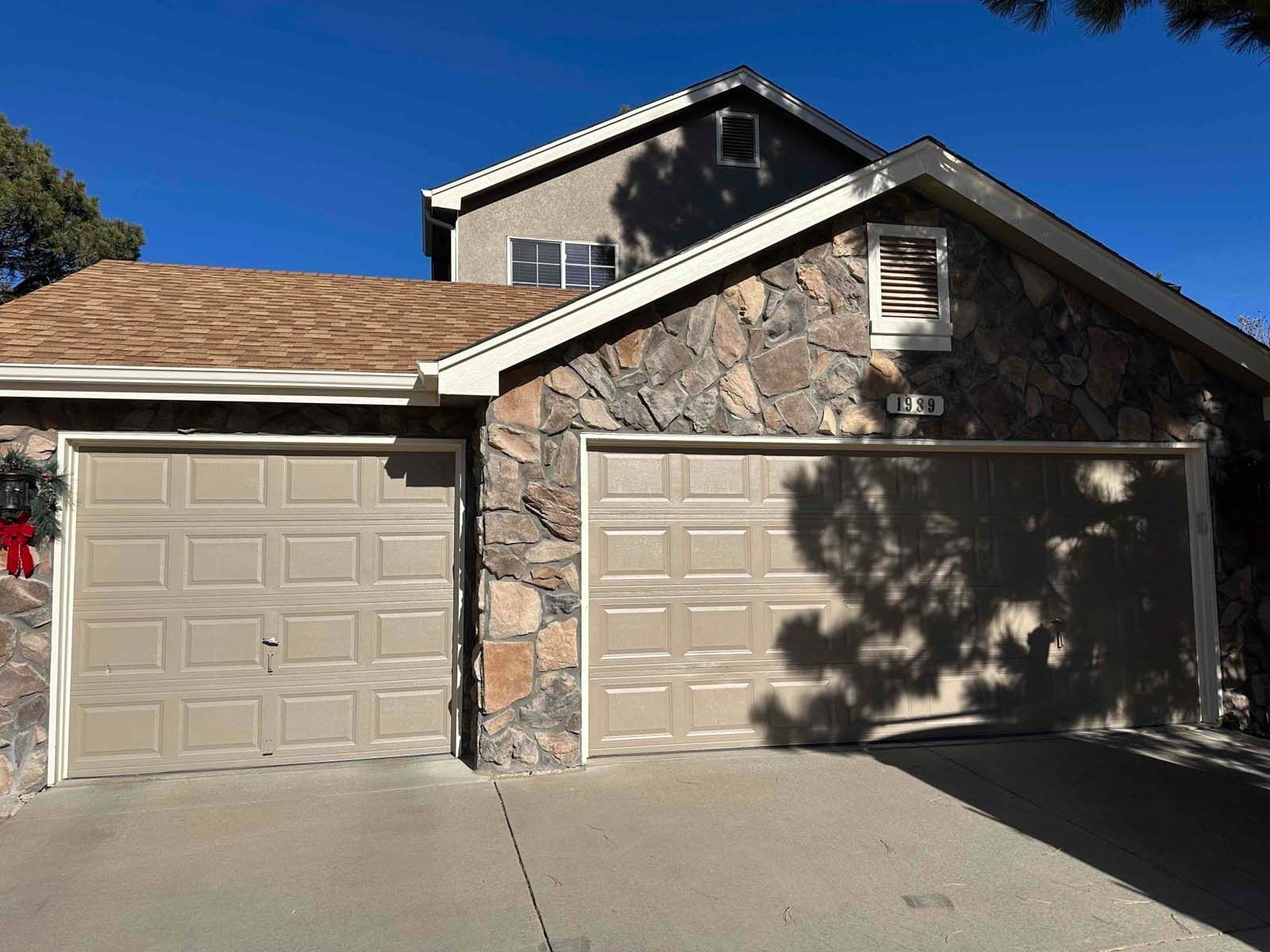 The front of a house with two garage doors and a stone wall.