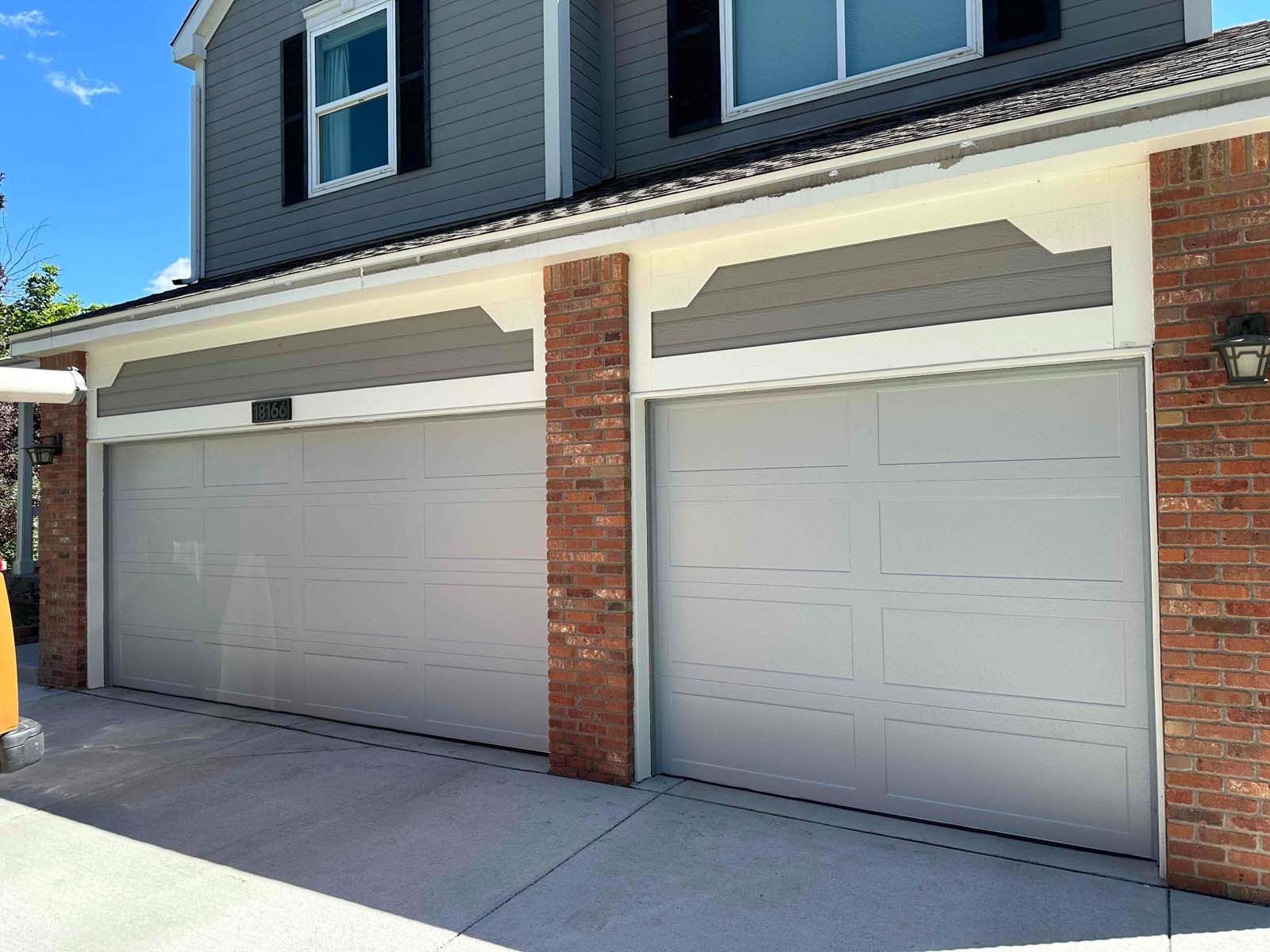 A house with two garage doors and a brick wall