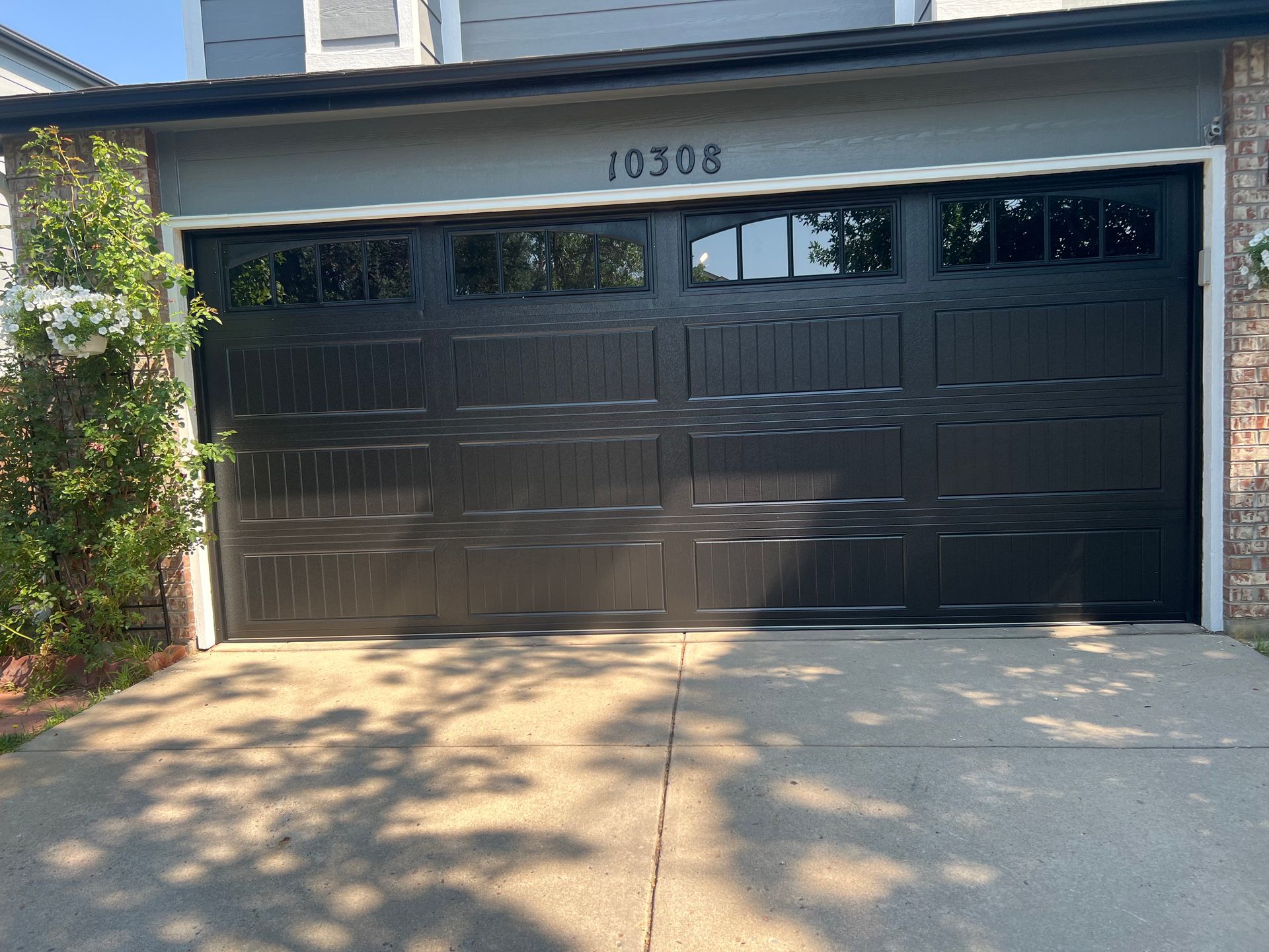 Black garage door with glass windows and house numbers 10308.