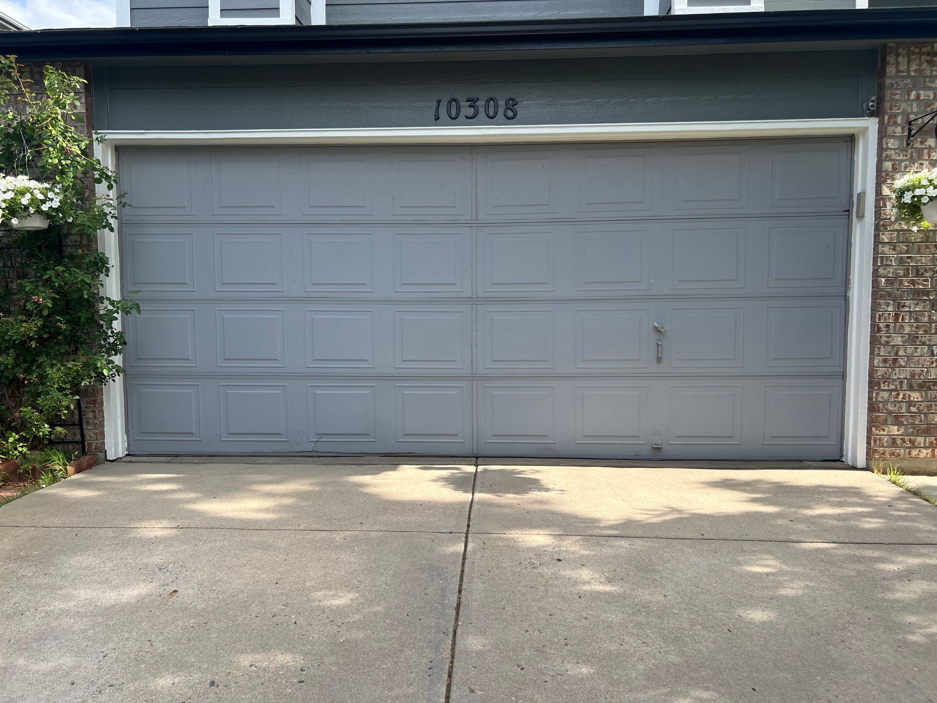 Gray garage door with address numbers 10308 above, set in a concrete driveway.