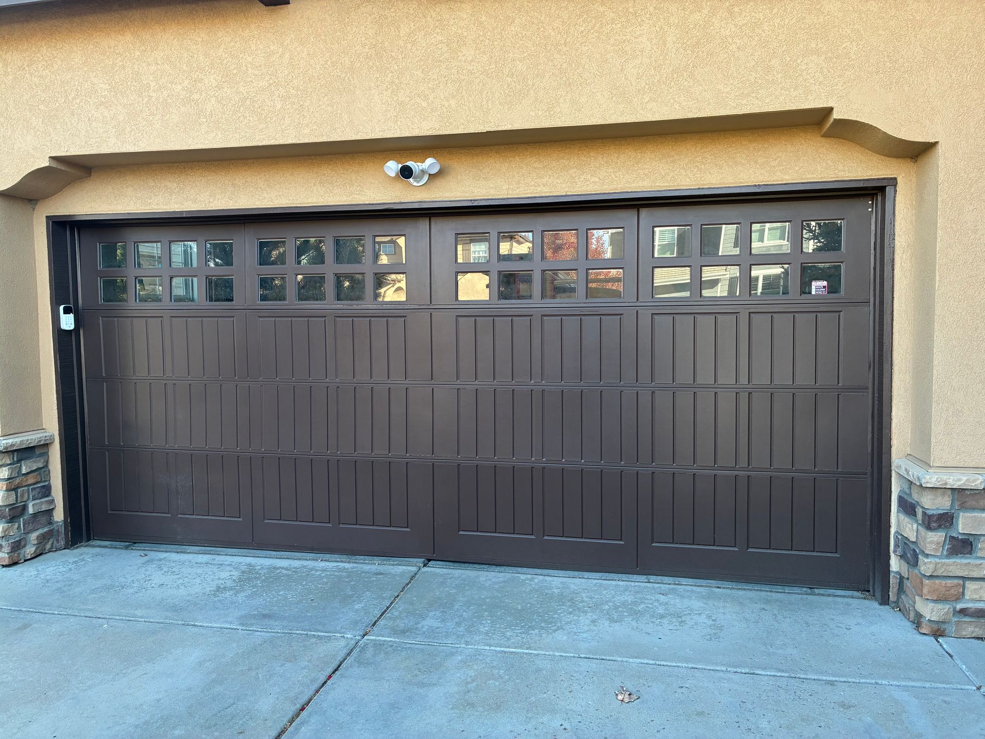 Brown garage door with windows, tan stucco exterior.