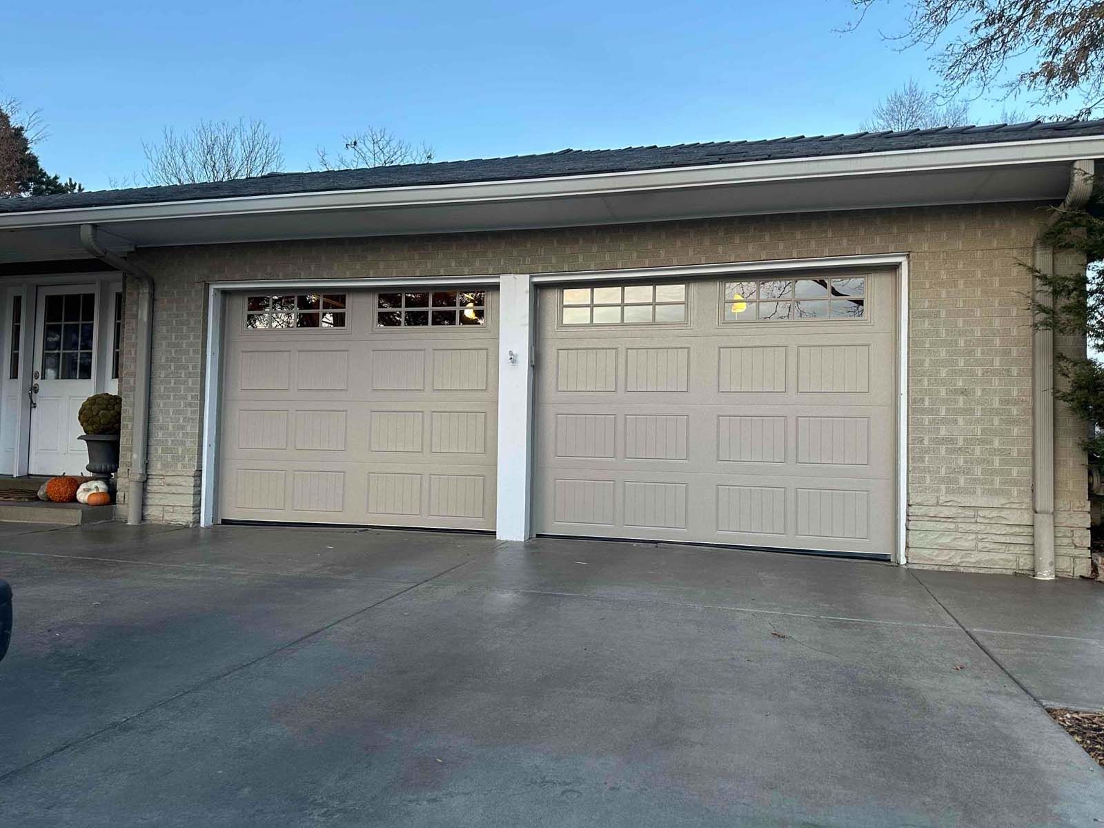 A house with two garage doors and a car parked in front of it.