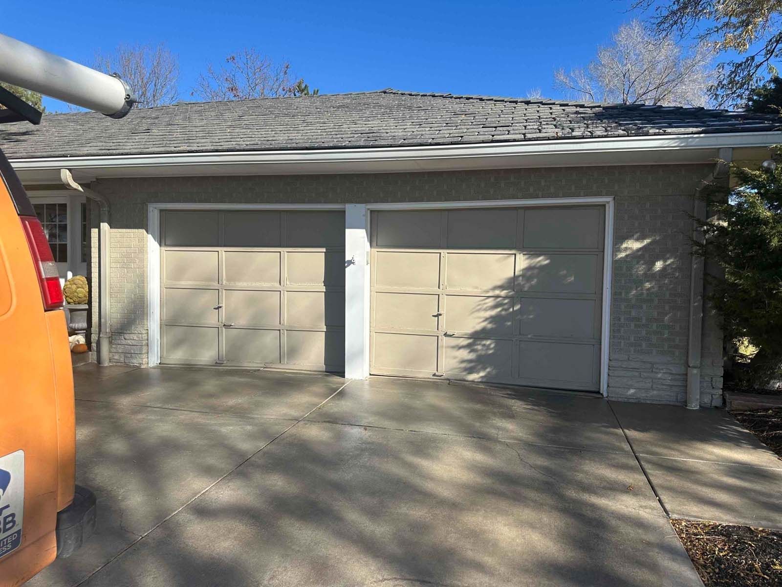 A truck is parked in front of a house with two garage doors.