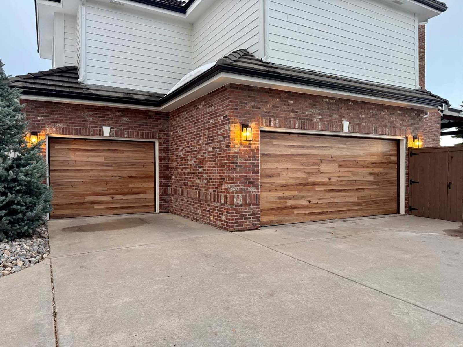 A large brick house with two wooden garage doors.