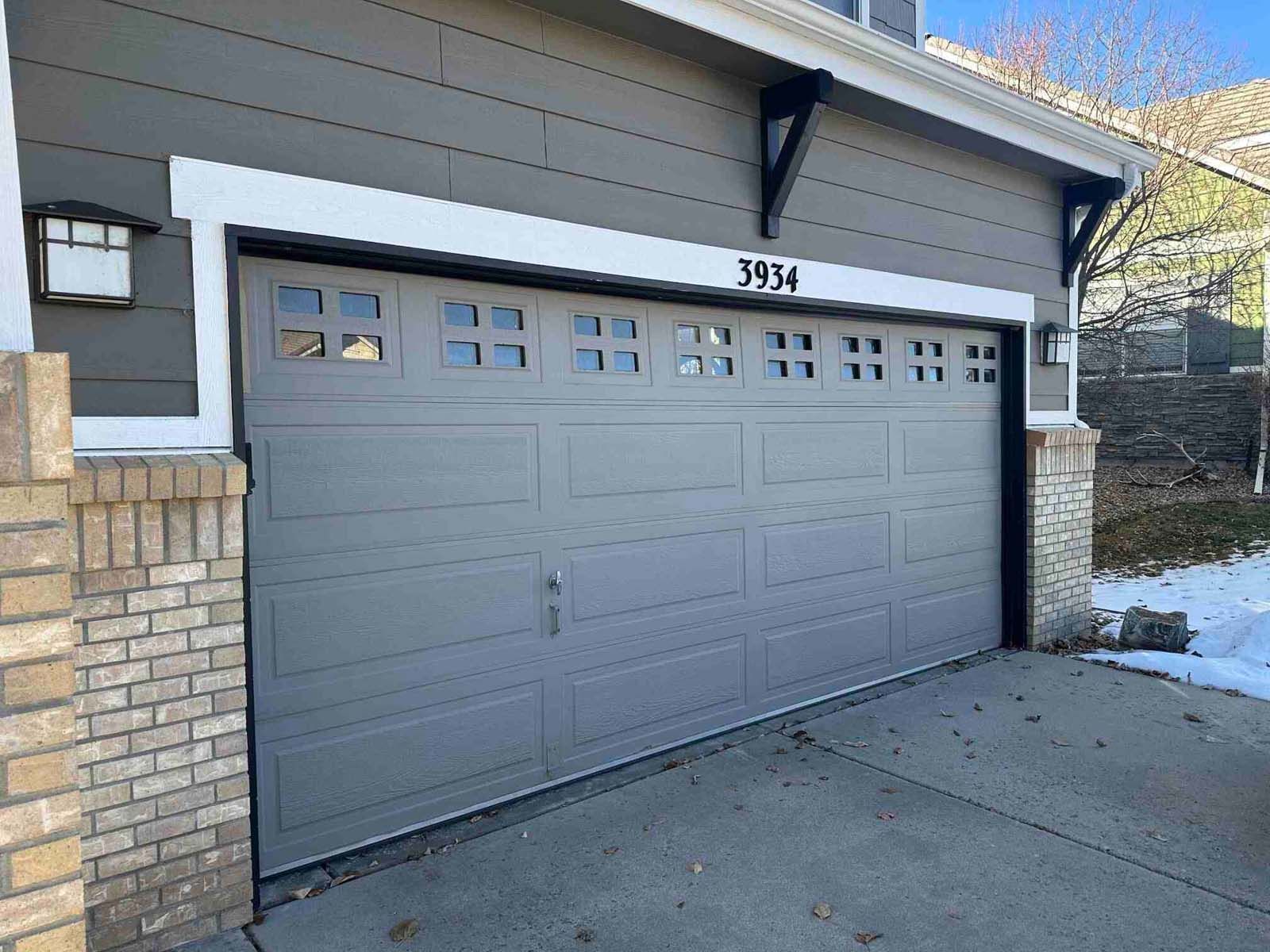 A gray garage door is sitting on the side of a house.