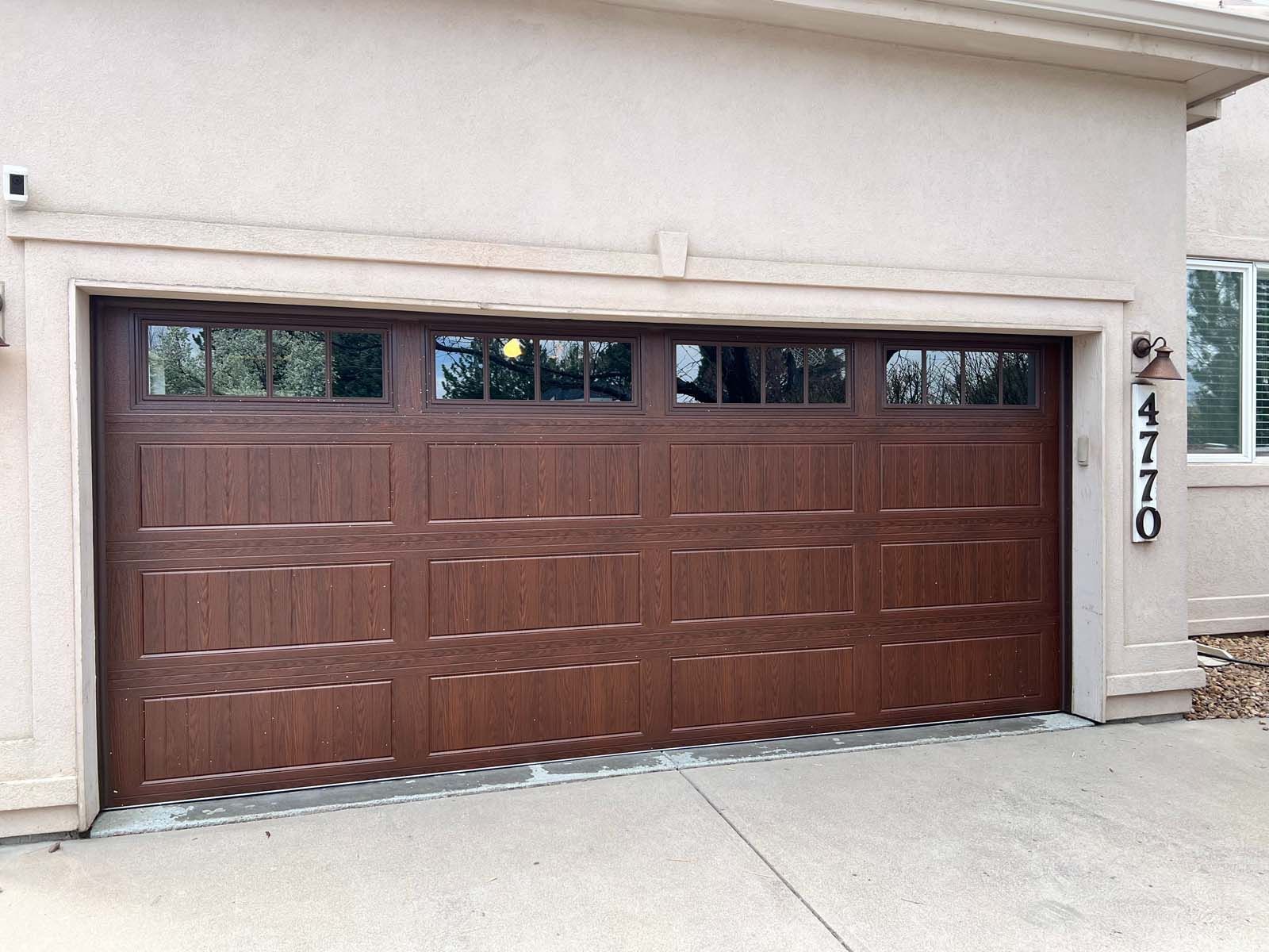 A large wooden garage door is sitting in front of a house.
