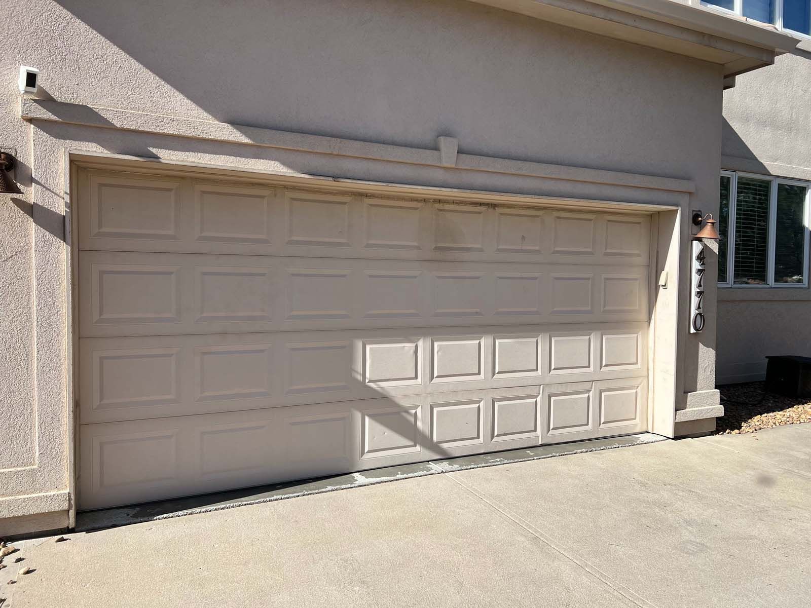 A white garage door is open in front of a house