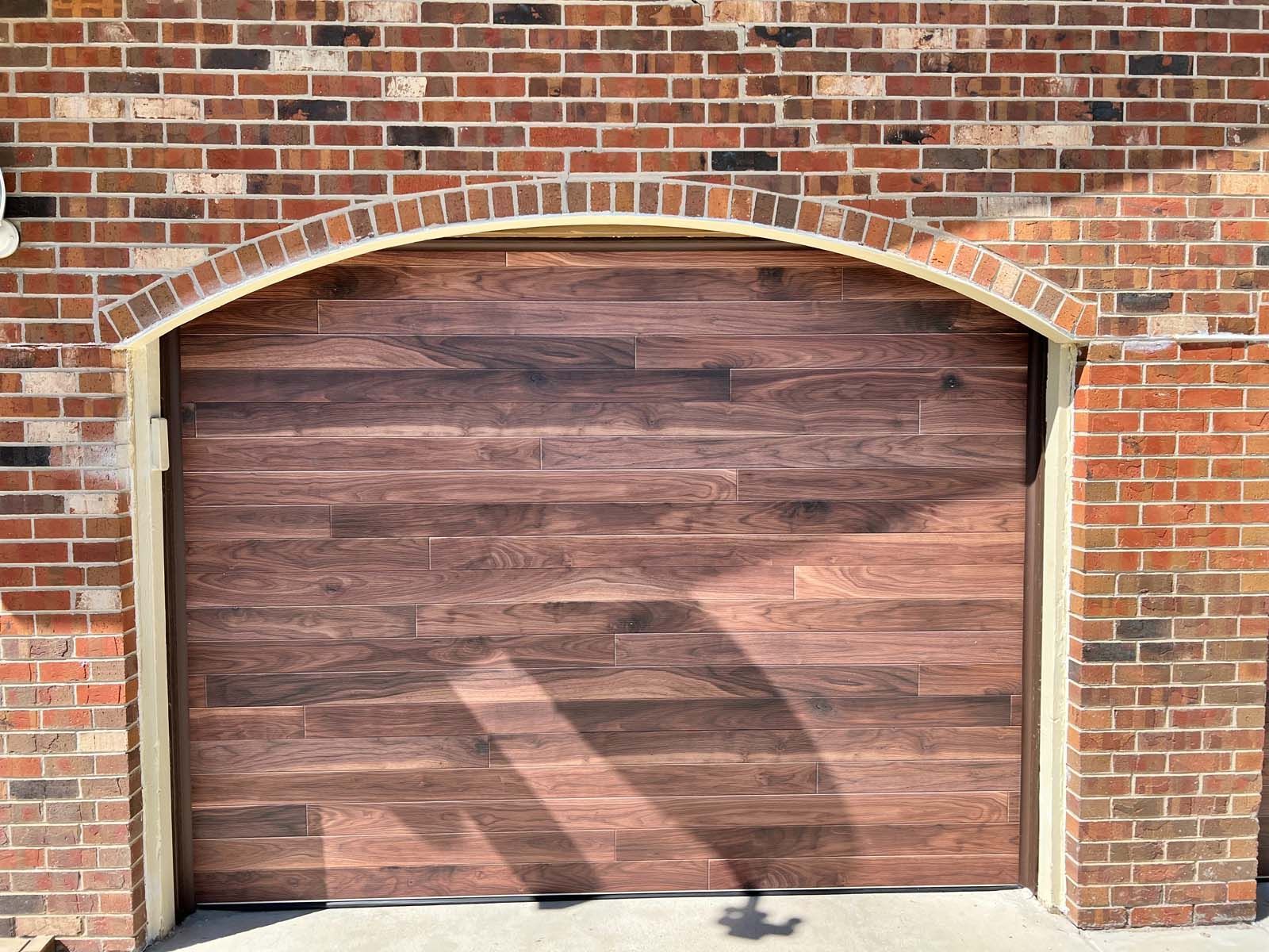 A wooden garage door is sitting in front of a brick wall.