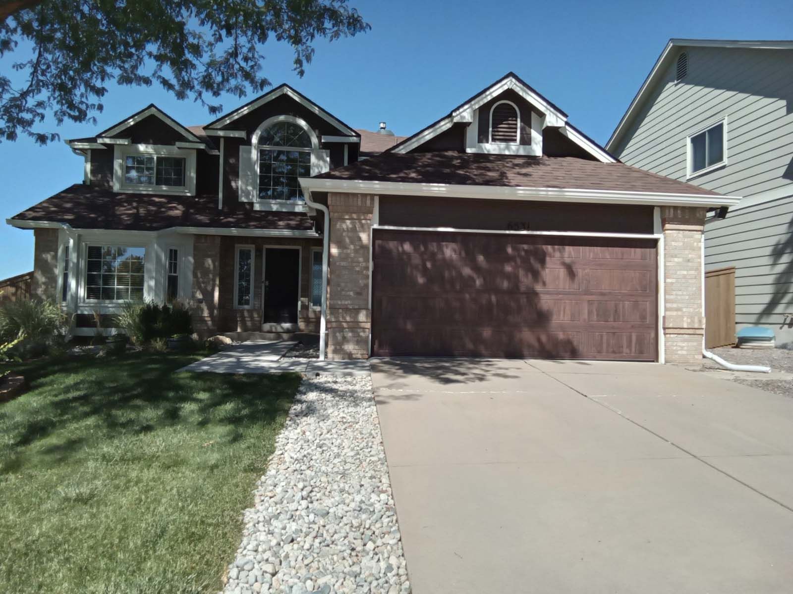 A large house with a brown garage door and a driveway