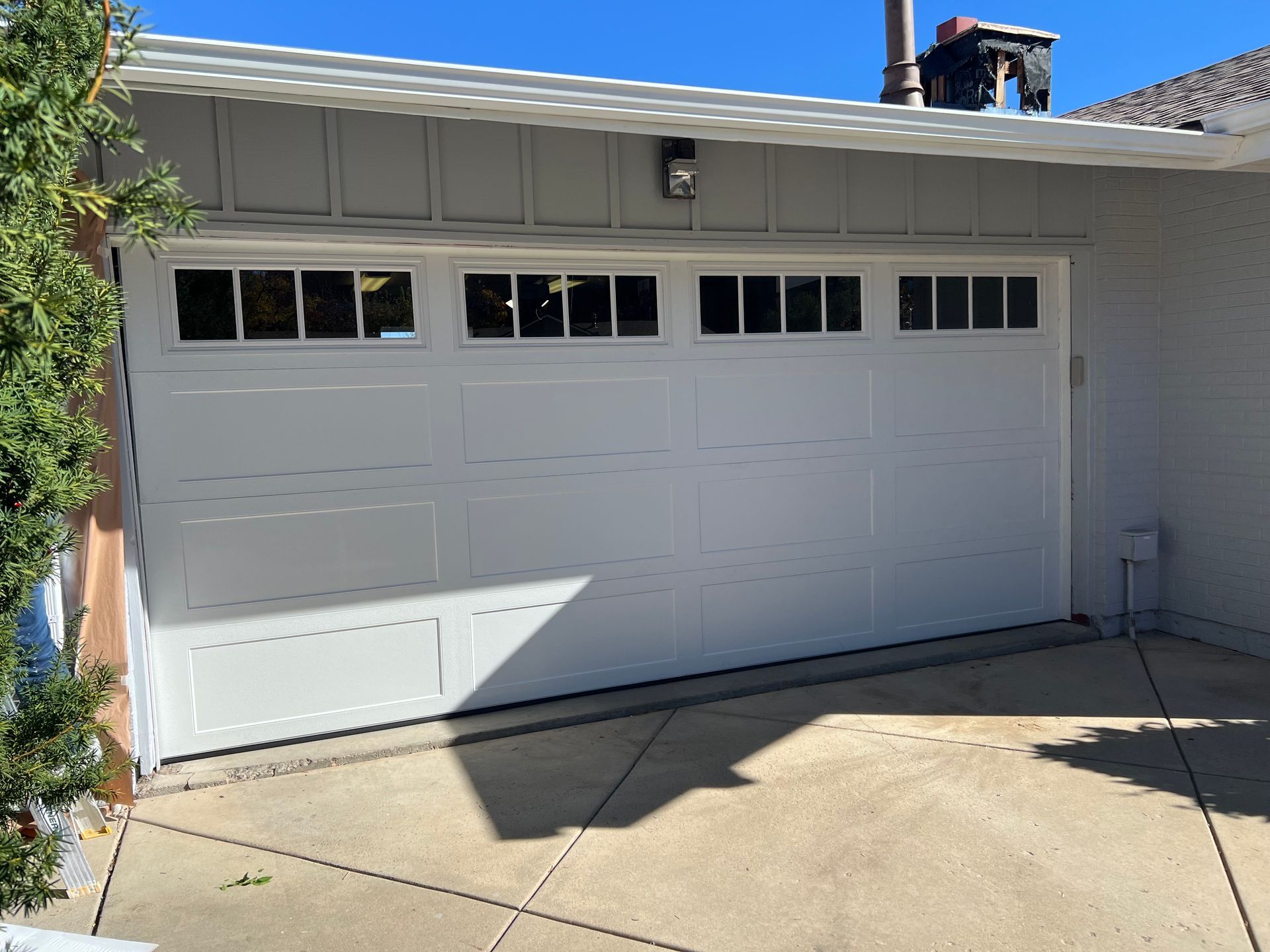 White garage door with windows, in front of a house, on a sunny day.