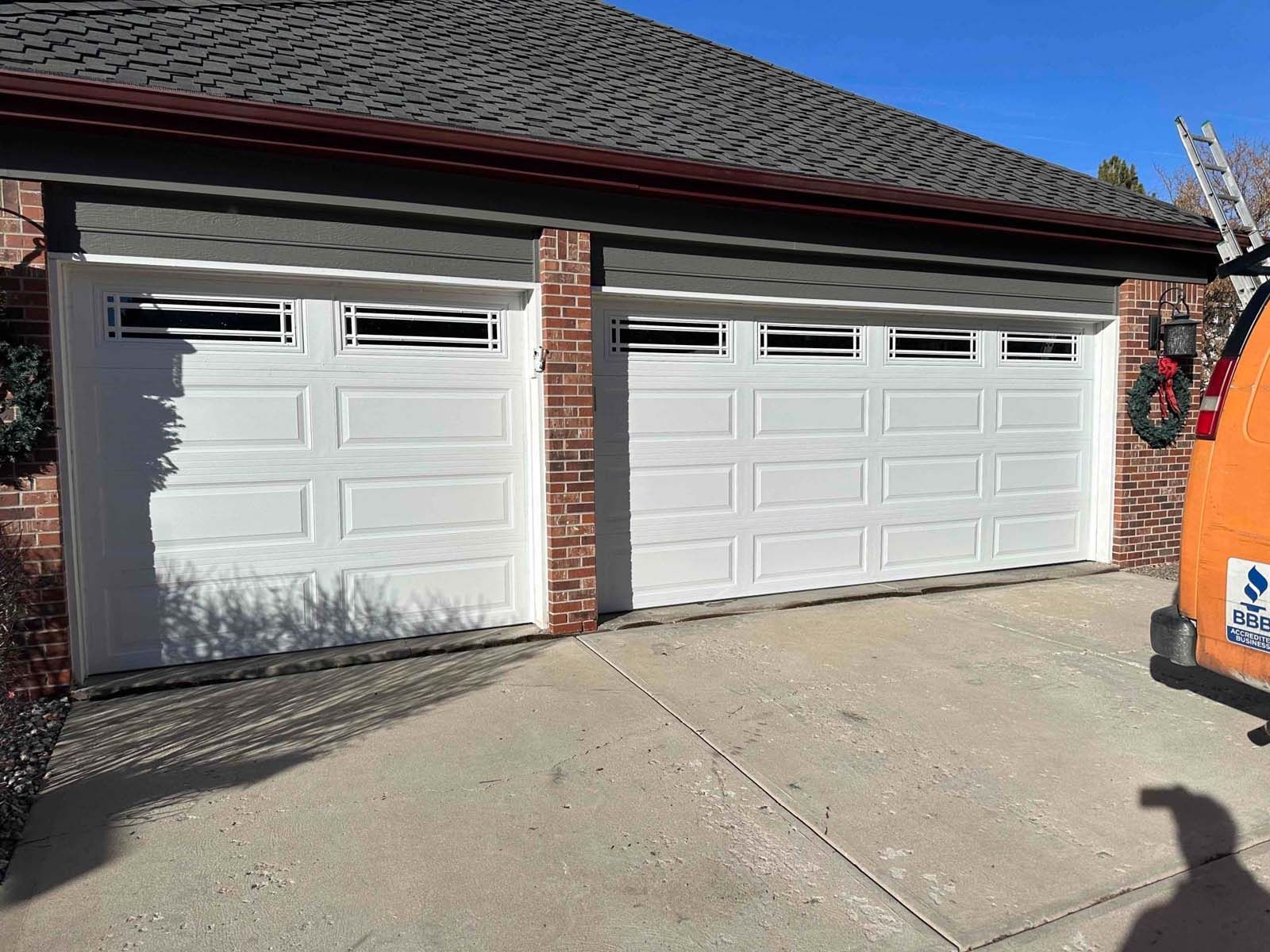 There is a van parked in front of a garage door.