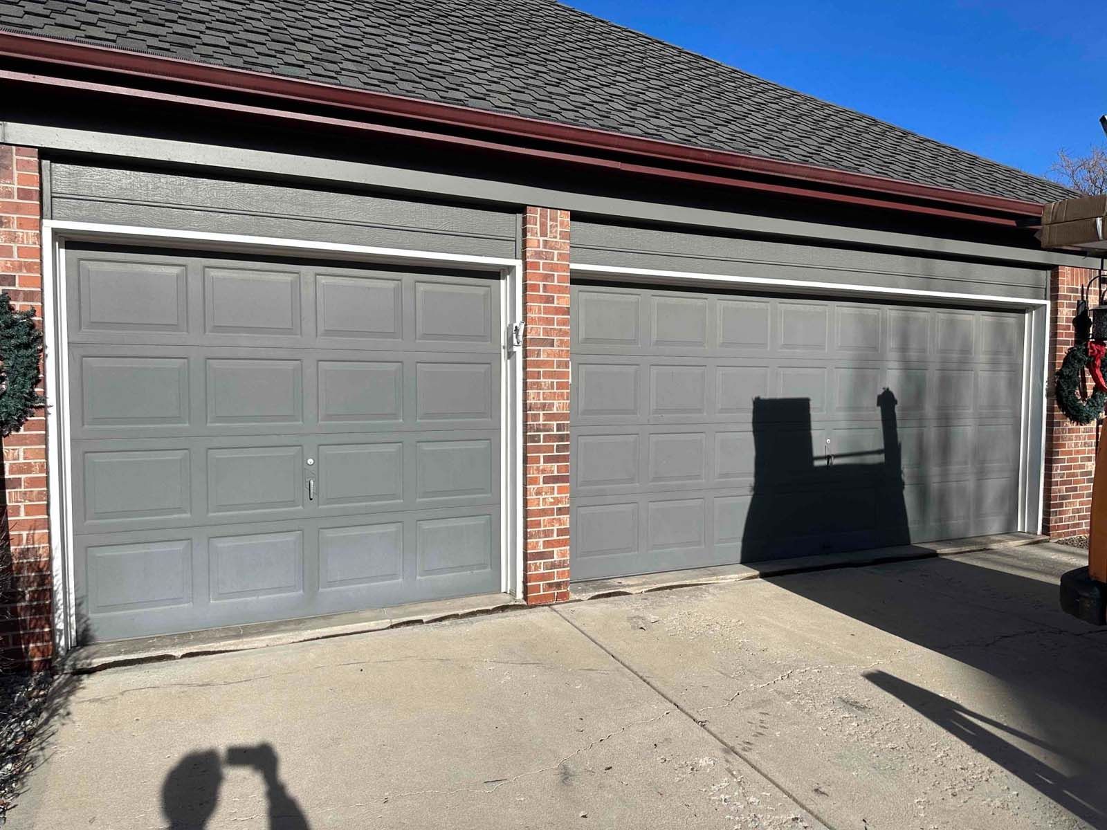 There is a shadow of a person standing in front of a garage door.