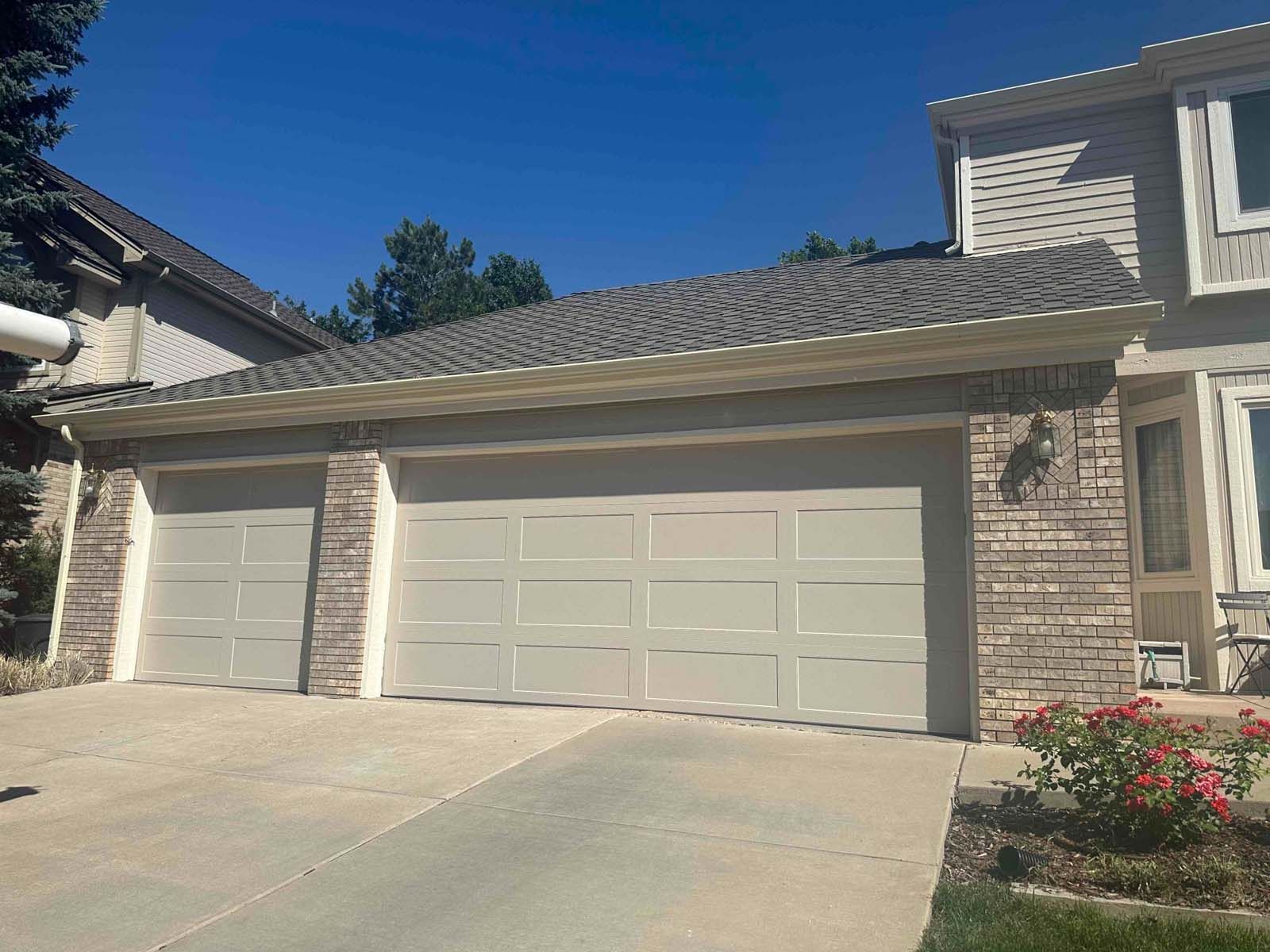 A large house with three garage doors and a driveway.