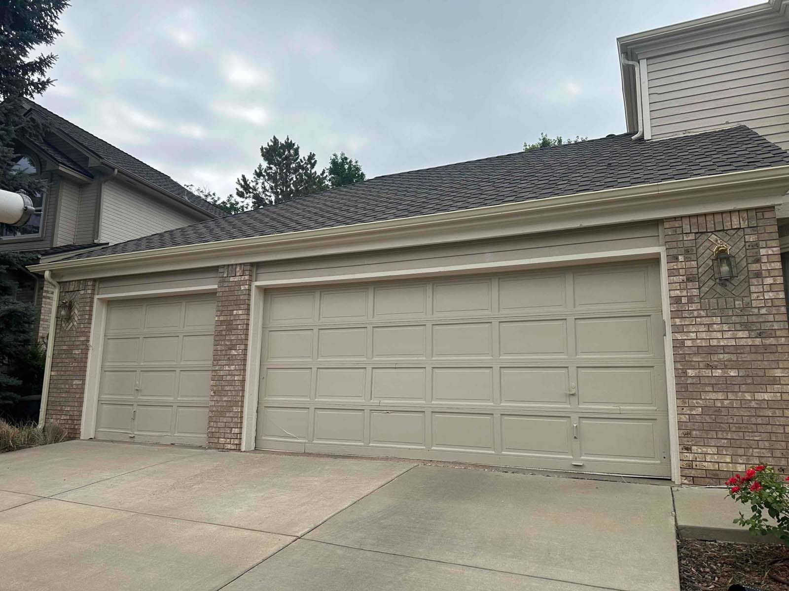 A house with three garage doors and a brick wall.