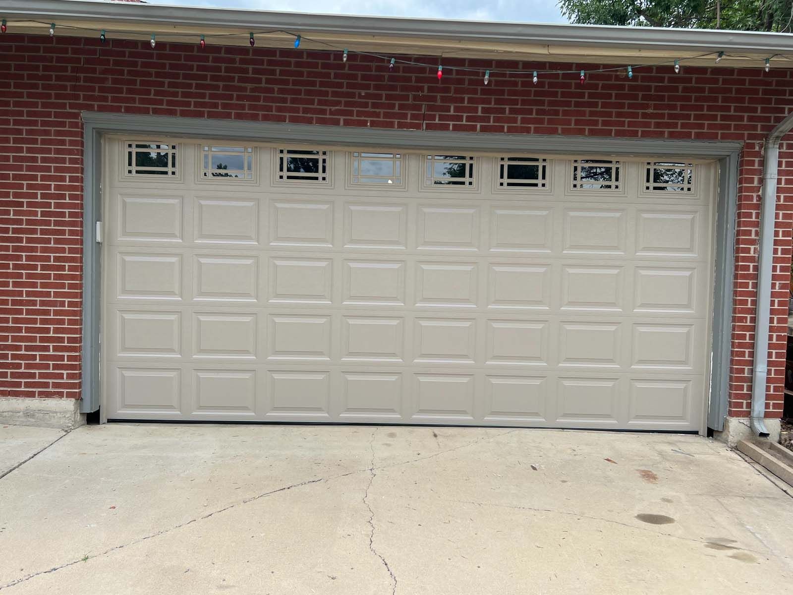 A white garage door is against a red brick wall