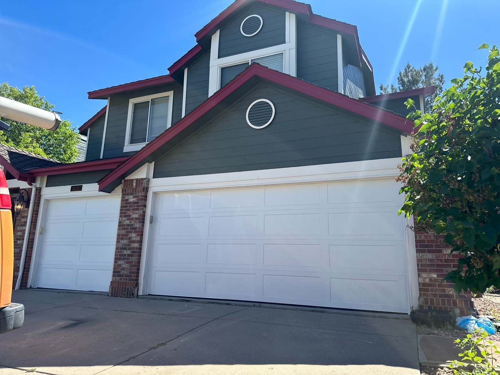 A large house with three garage doors and a red roof.