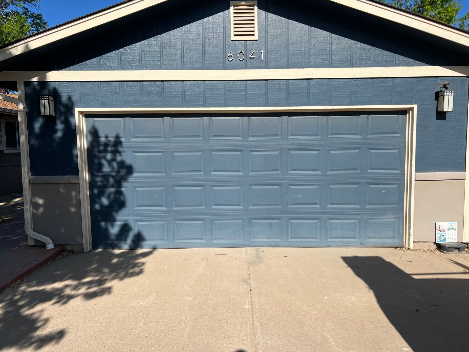 A blue garage door is sitting in front of a house.