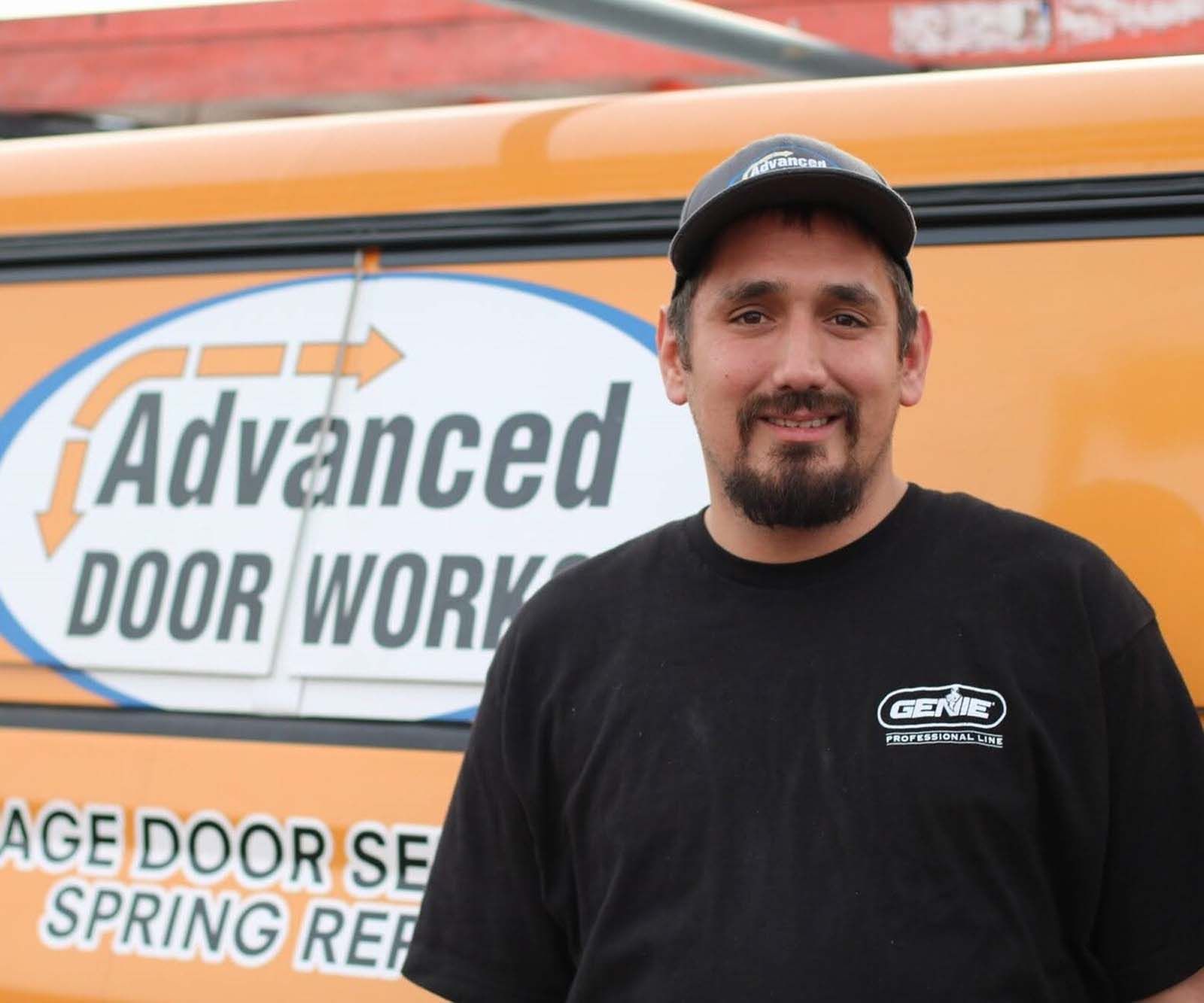 A man standing in front of an orange van that says advanced door work
