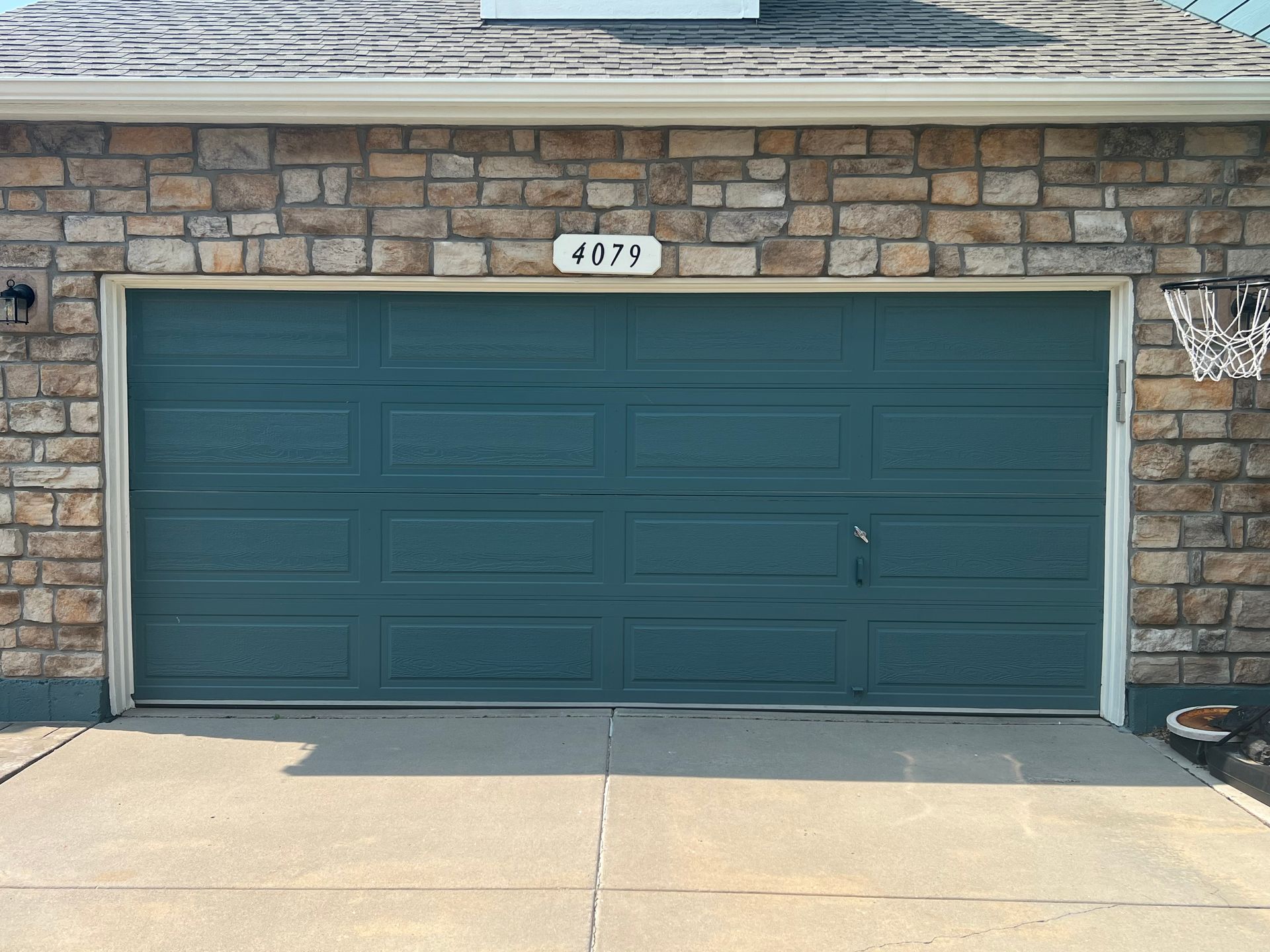 Blue garage door on a stone brick house; address 
