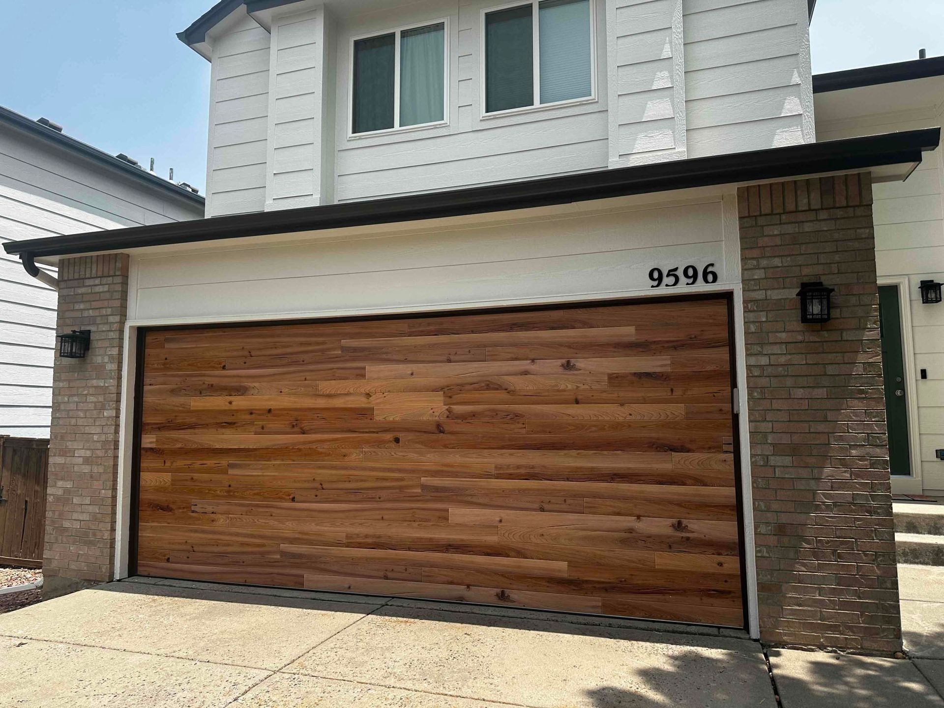 A wooden garage door installed on a white house.