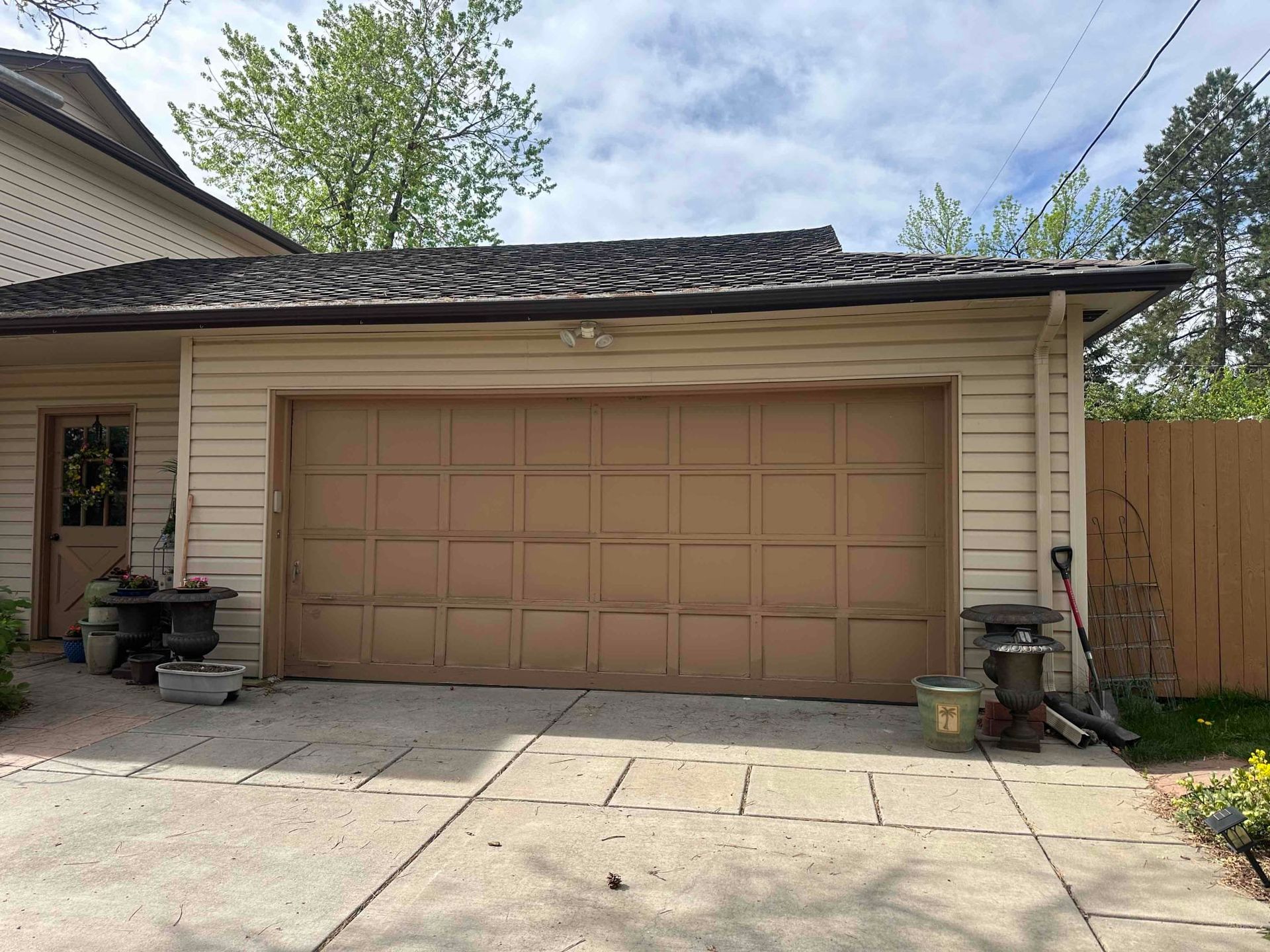 A brown garage door is sitting in front of a house.
