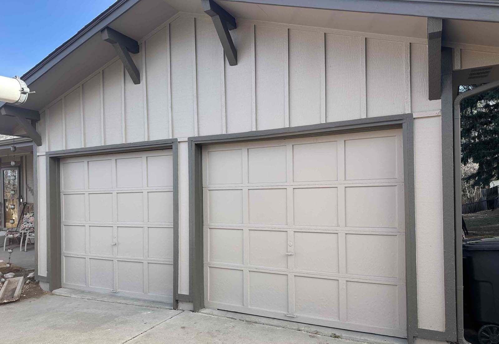 There are two garage doors on the side of a house.