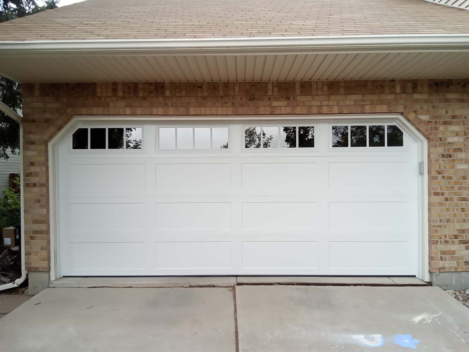 A white garage door on a brick house
