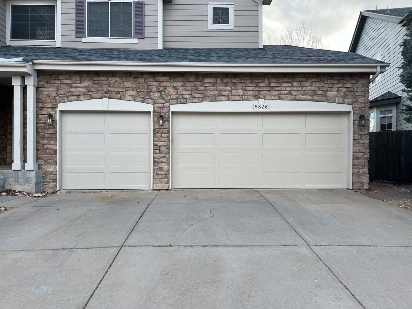 There are two garage doors in front of a house.