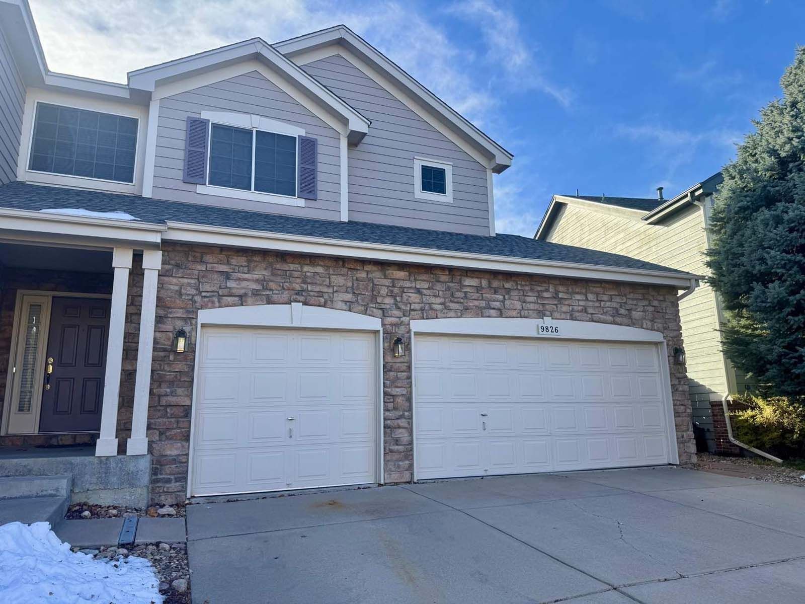 A large house with two garage doors and a driveway.