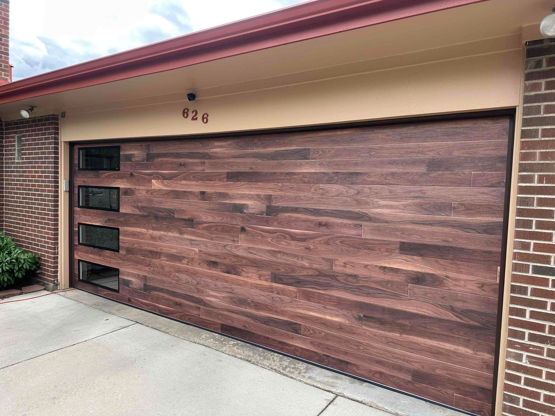 A wooden garage door is sitting on the side of a brick building.
