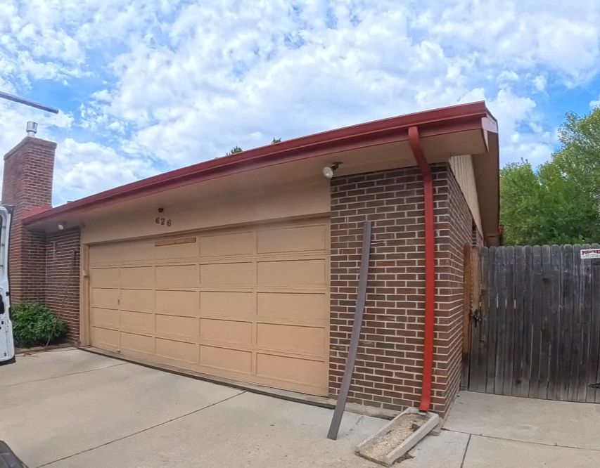 A garage with a brick wall and a red gutter.