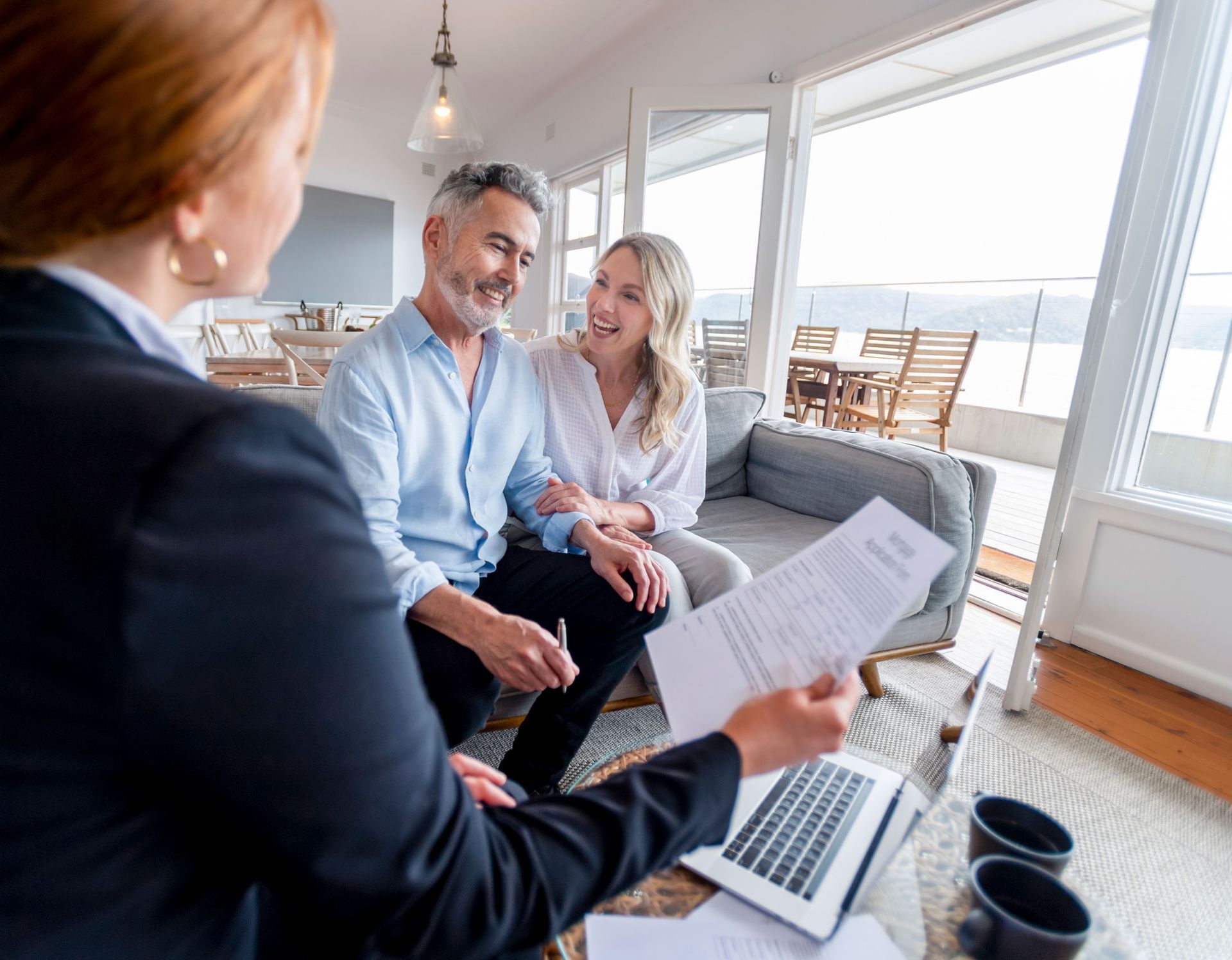 A woman is sitting on a couch talking to a man and woman.