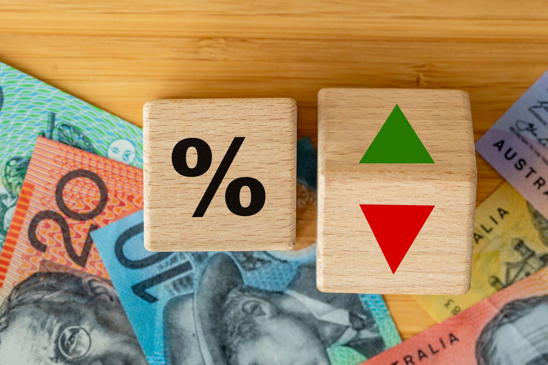 A wooden block with a percent sign on it is sitting on top of a pile of money.