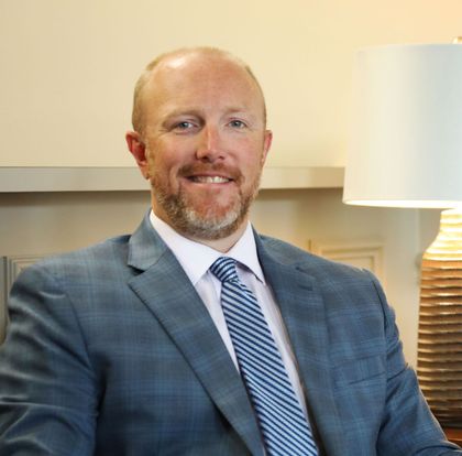 A man in a suit and tie is smiling for the camera