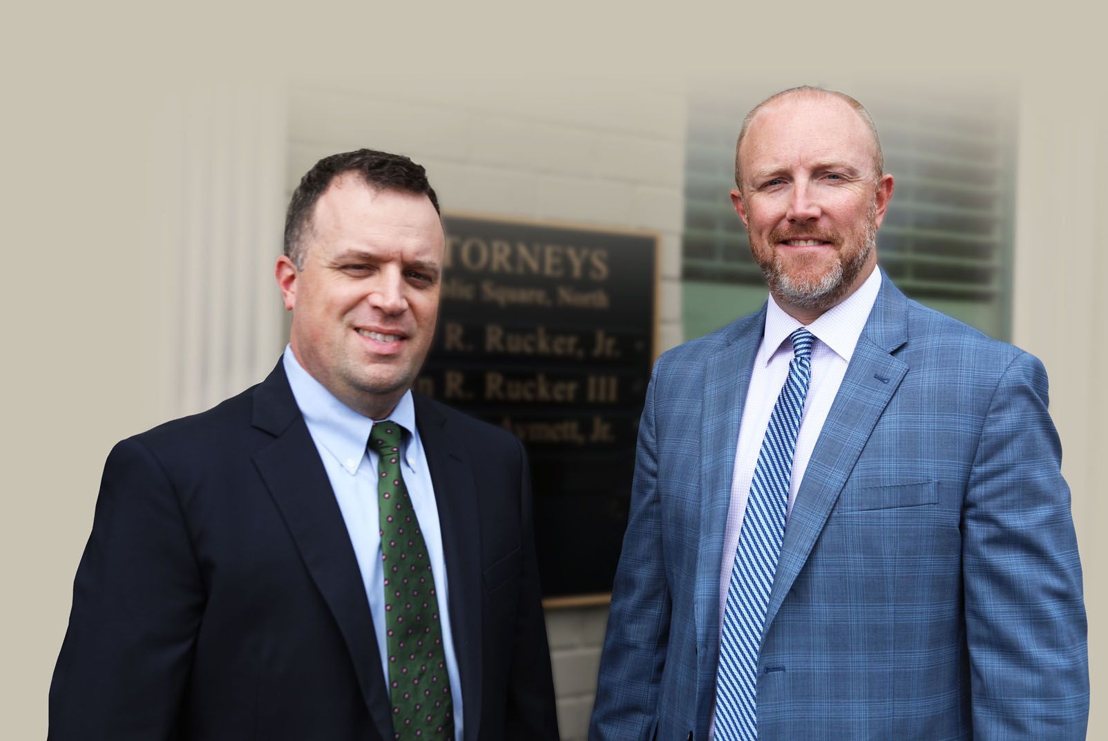 Two men in suits and ties are standing next to each other in front of a building.