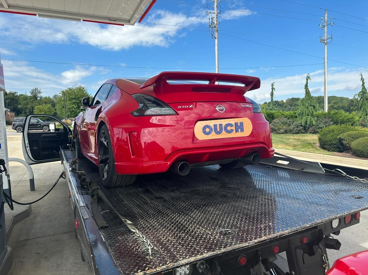 Red Nissan 370Z being towed on a flatbed truck, 