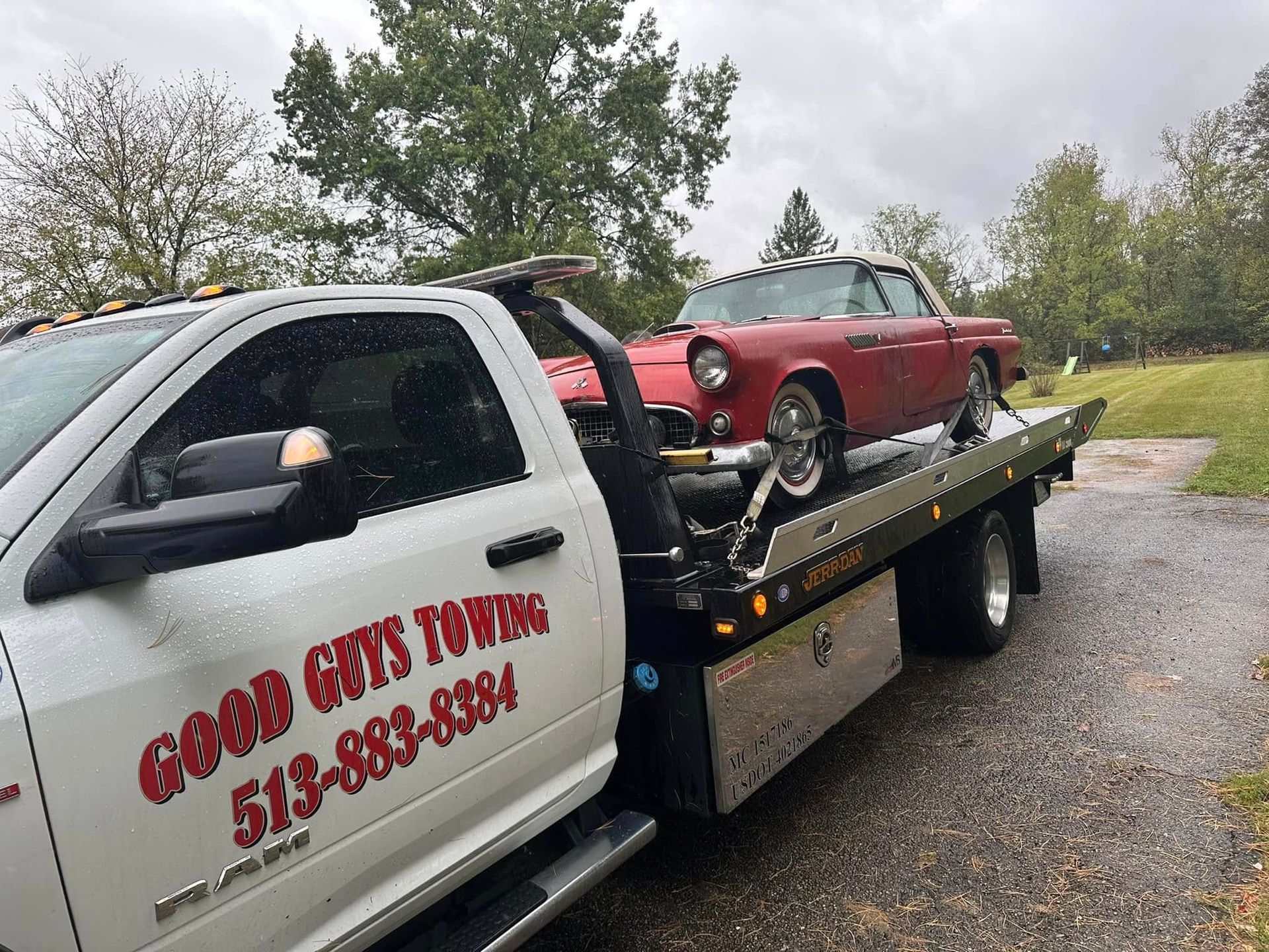 Red classic car towed by a white tow truck with 