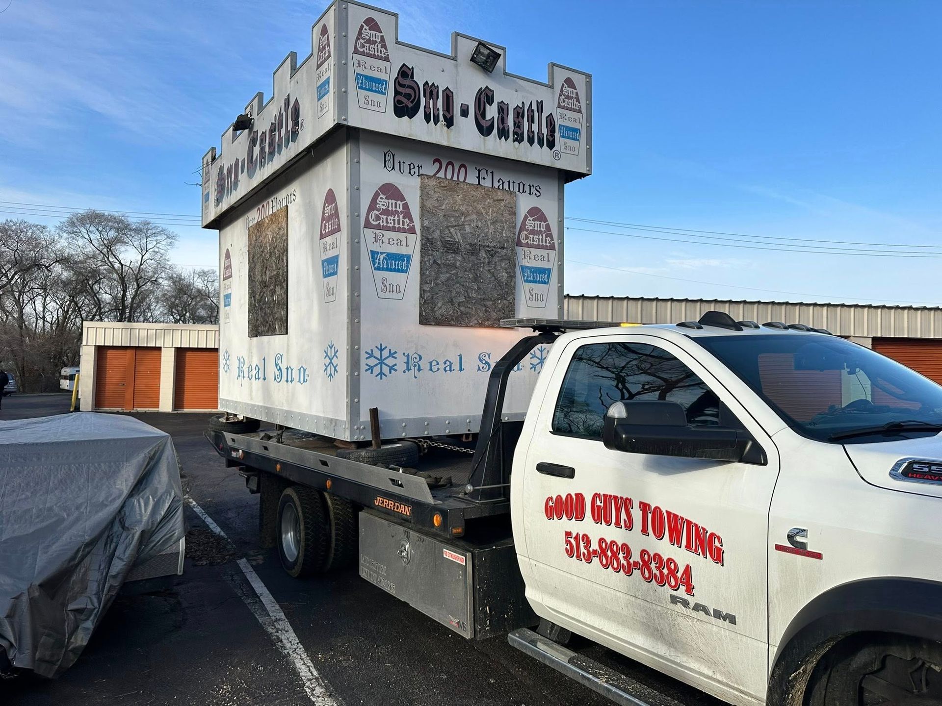 A tow truck carrying a castle-shaped building, labeled 