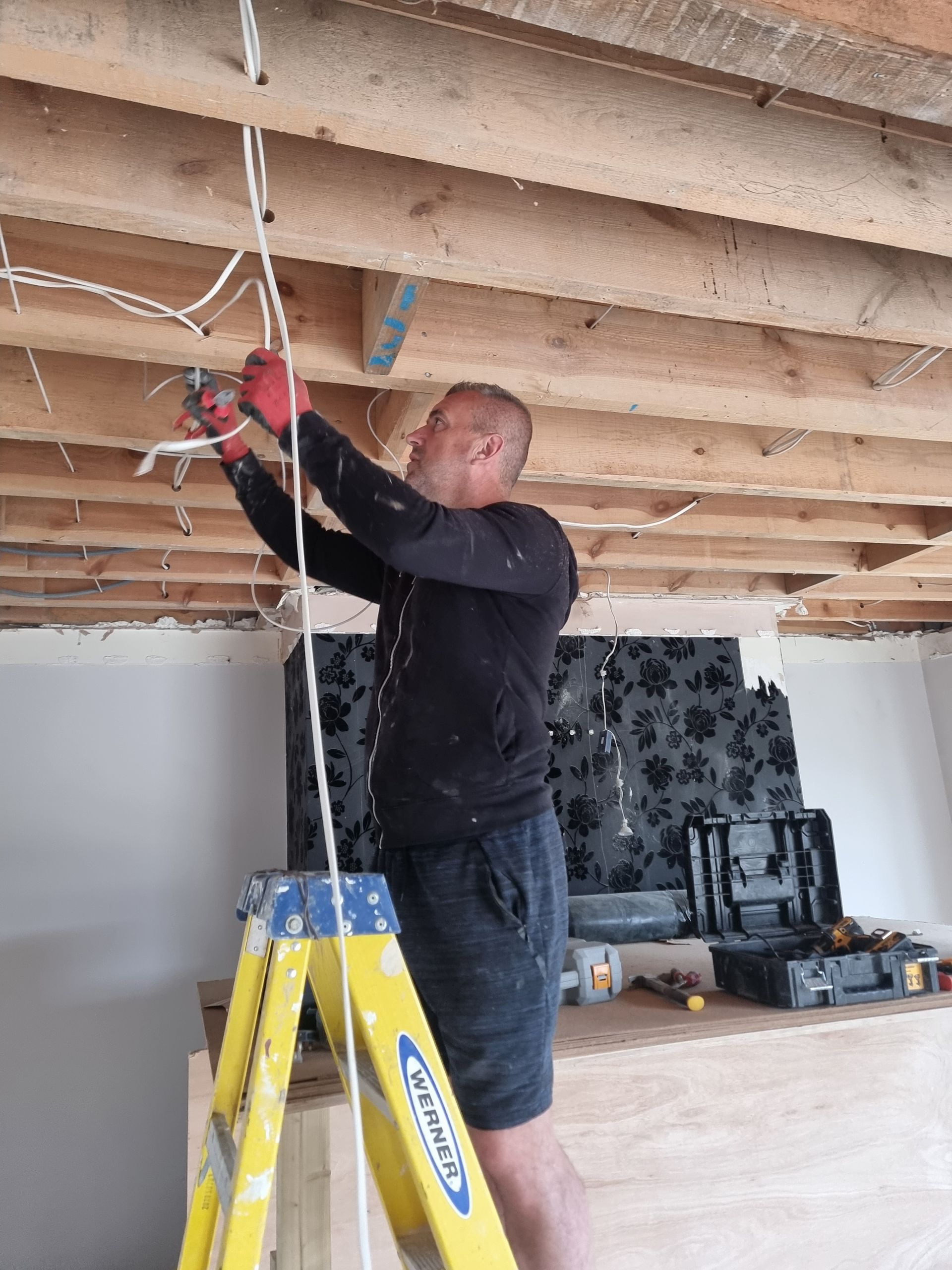 A man is standing on a ladder working on a ceiling.