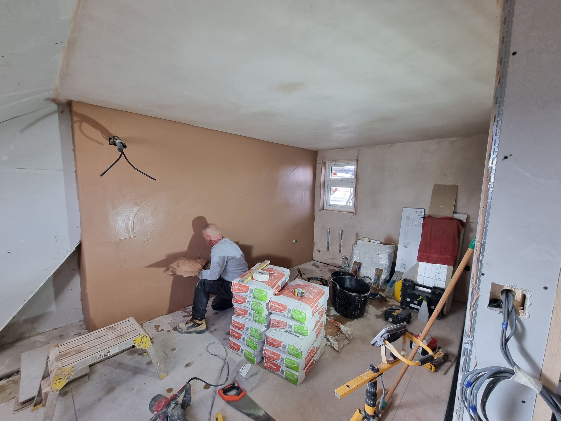 A man is working on a wall in a room.