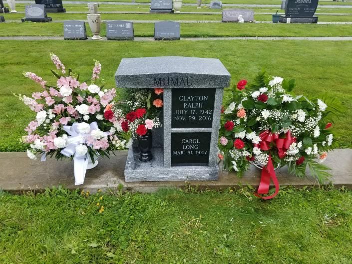 Memorial gravestone with pink and red flower arrangements in a cemetery