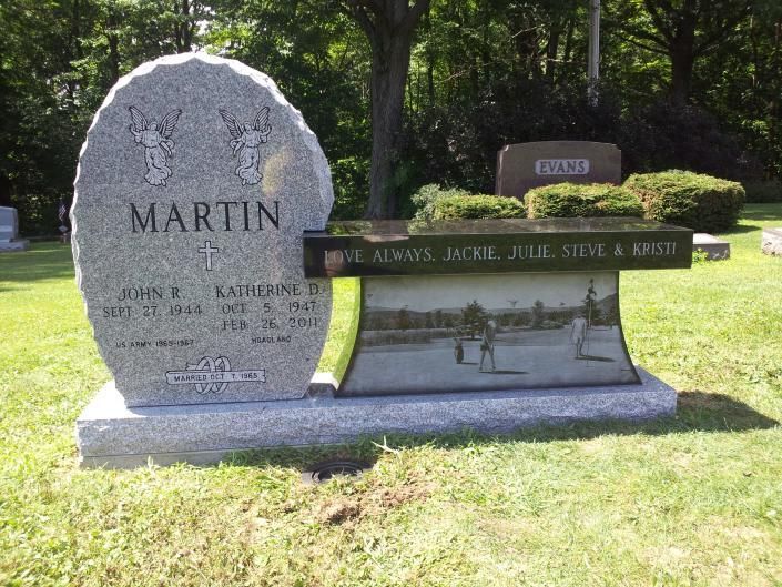 Gravestone memorial in a sunny cemetery with polished black base and a large stone marker engraved MARTIN.